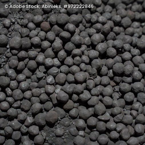 Nahaufnahme von kugelförmigen Eisenerzpellets mit unregelmäßiger Oberfläche